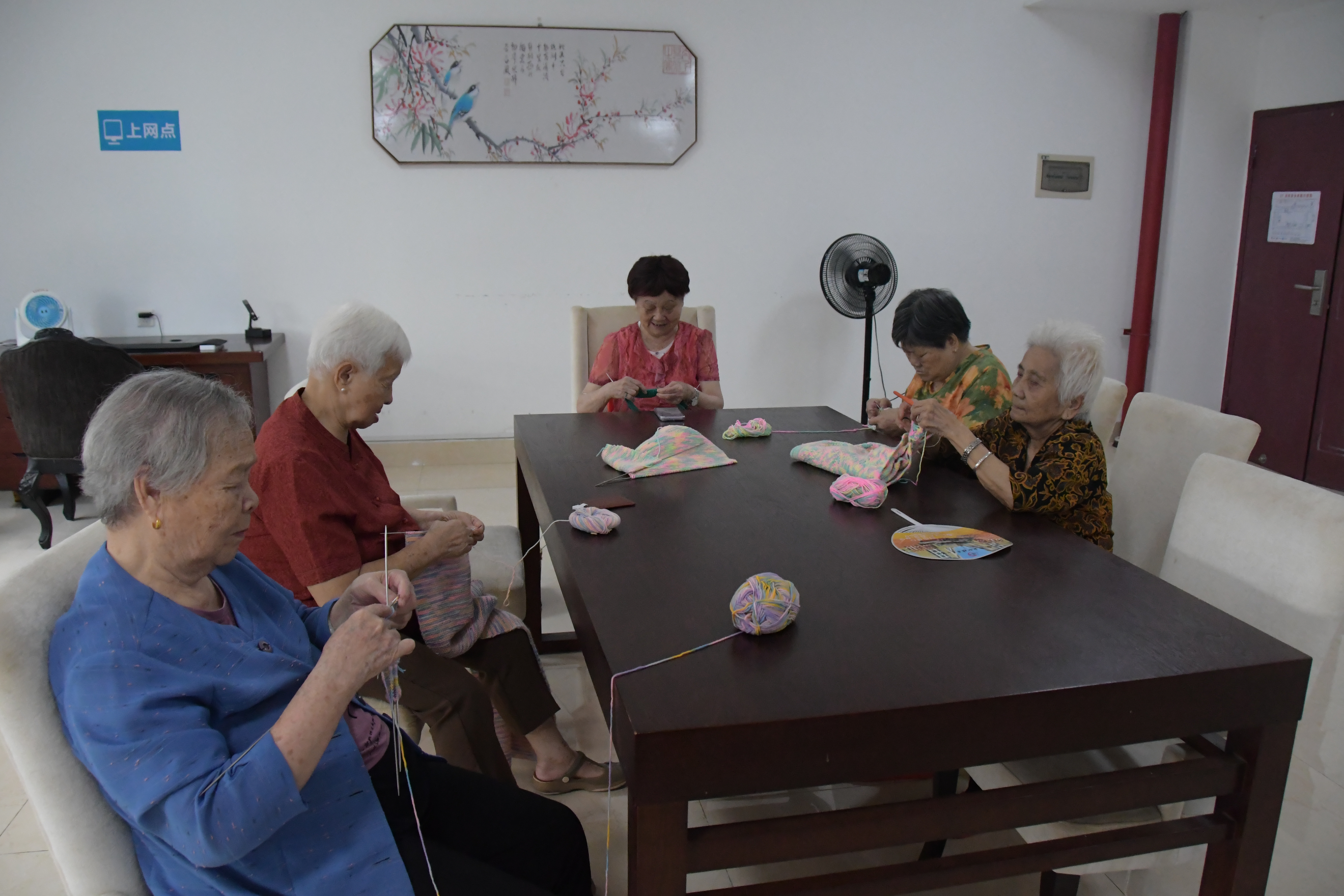 长者围坐桌边参与毛线编织